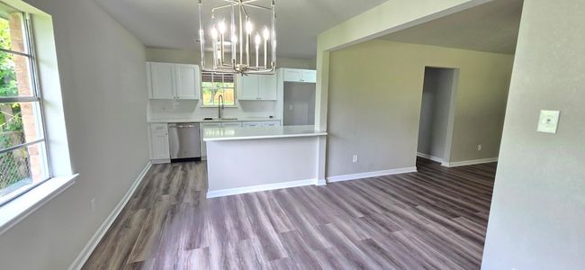 Dining room is open to the kitchen and living room. It boasts a gorgeous brushed nickel modern chandelier. | Image 6