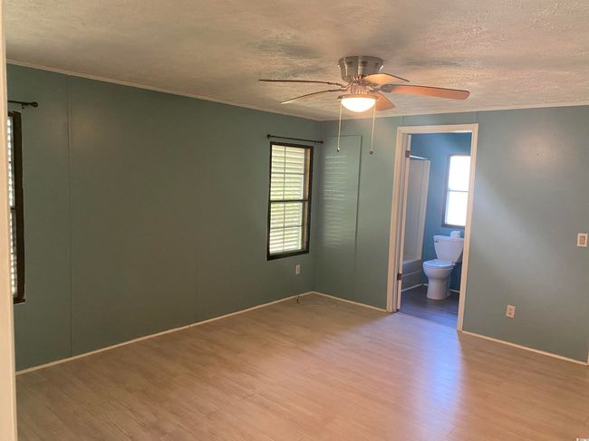 Unfurnished room with a textured ceiling, light wood-style flooring, ornamental molding, and a ceiling fan | Image 21