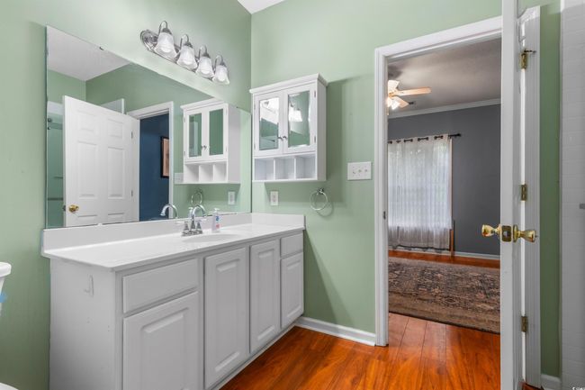 Bathroom with wood finished floors, a ceiling fan, vanity, baseboards, and ornamental molding | Image 26