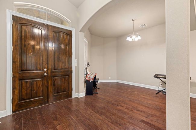 Entrance foyer with arched walkways, wood finished floors, and a chandelier | Image 4