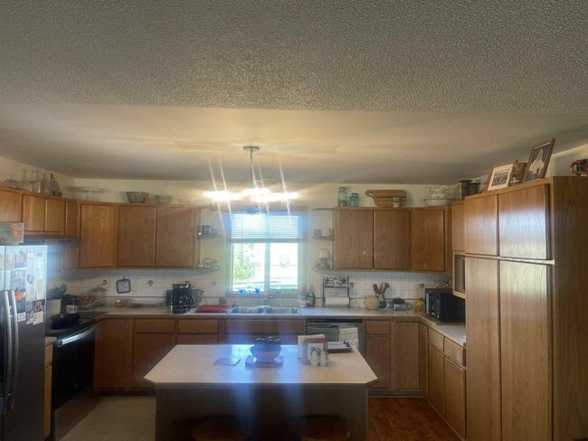 Kitchen featuring open shelves, stainless steel appliances, light countertops, tasteful backsplash, and a kitchen island | Image 4