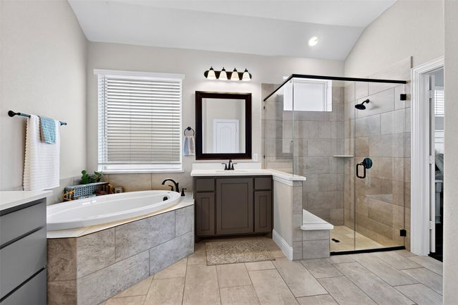 Full bathroom featuring vanity, a bath, a stall shower, lofted ceiling, and tile patterned flooring | Image 17