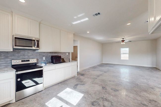 Kitchen with visible vents, decorative backsplash, baseboards, and stainless steel appliances | Image 18