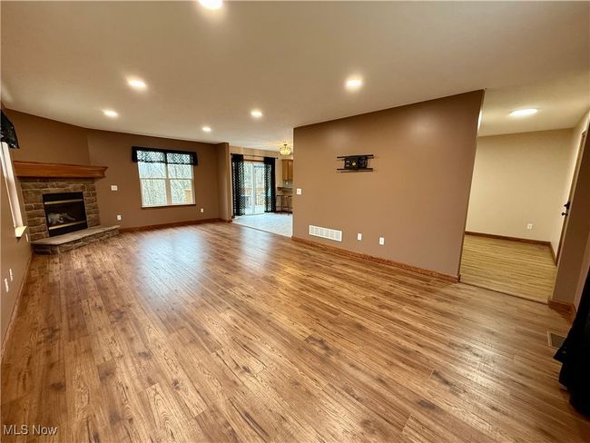 Unfurnished living room with light wood finished floors, recessed lighting, baseboards, and a fireplace | Image 12