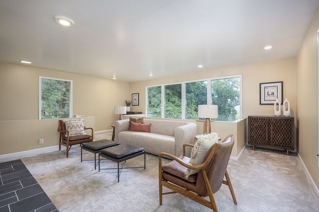 Centered around a statement fireplace, it’s the perfect spot to unwind or entertain. Oversized windows frame breathtaking views of the rolling hills, making this den feel like a cozy perch above nature. | Image 15