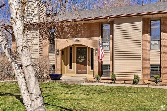 Property entrance with a yard, brick siding, a chimney, and a shingled roof | Image 5