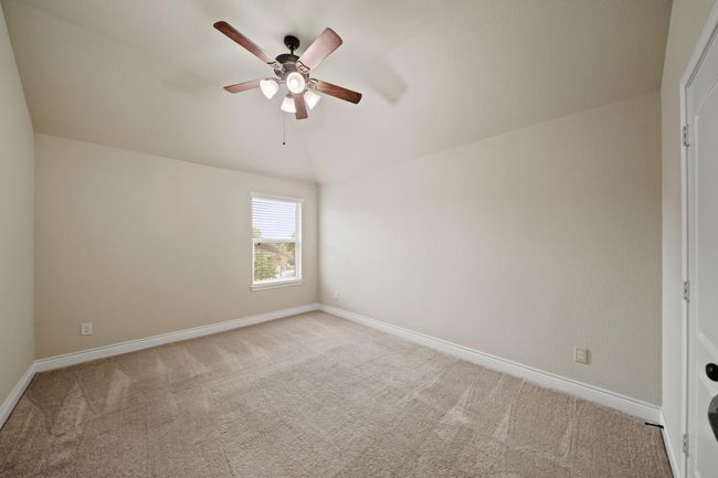 This is a cozy, carpeted bedroom with neutral walls, a ceiling fan, and a single window allowing natural light. | Image 32