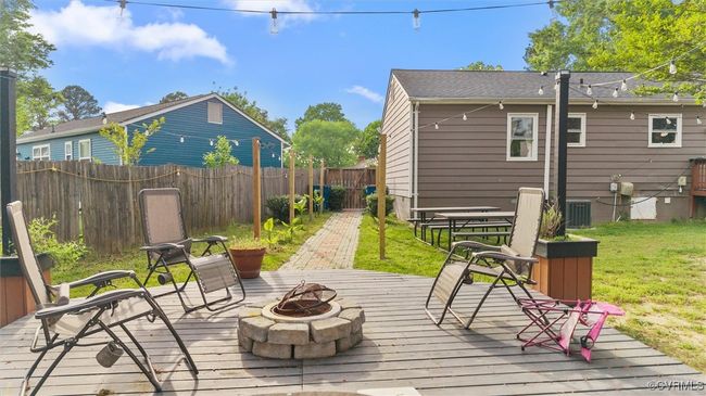 Wooden terrace with a lawn, central AC unit, a fenced backyard, and an outdoor fire pit | Image 30