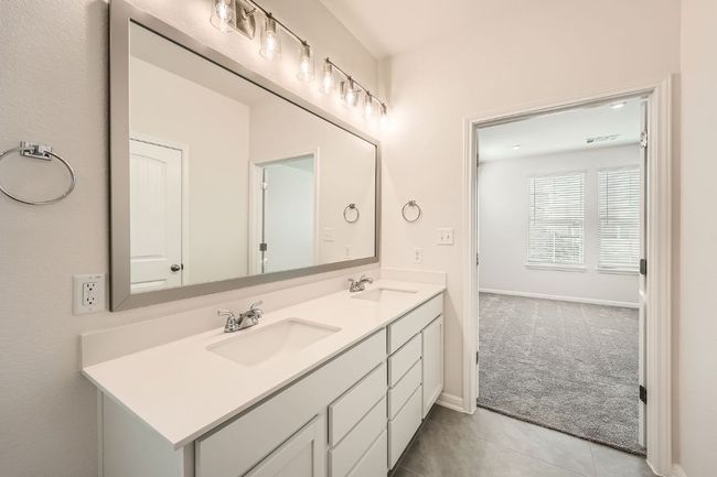 Bathroom with double vanity, tile patterned floors, baseboards, and a sink | Image 19