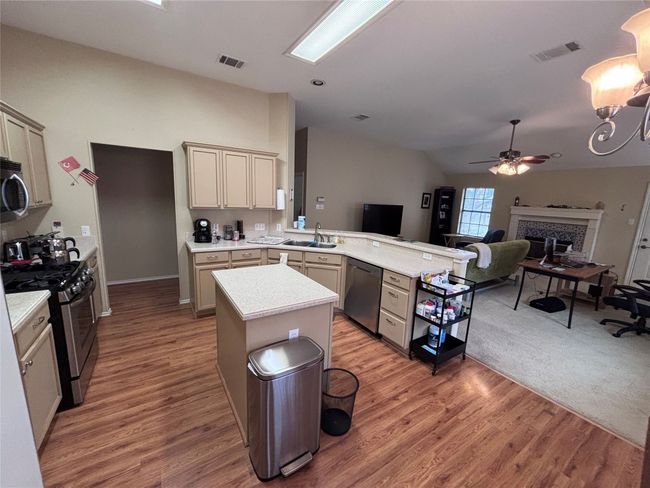 Kitchen featuring stainless steel appliances, lofted ceiling, a peninsula, ceiling fan, and light countertops | Image 6
