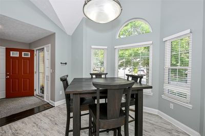 Dining room featuring light wood-type flooring, a textured ceiling, and high vaulted ceiling | Image 3