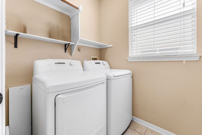 Washroom with washing machine and clothes dryer, light tile patterned floors, and baseboards | Image 32