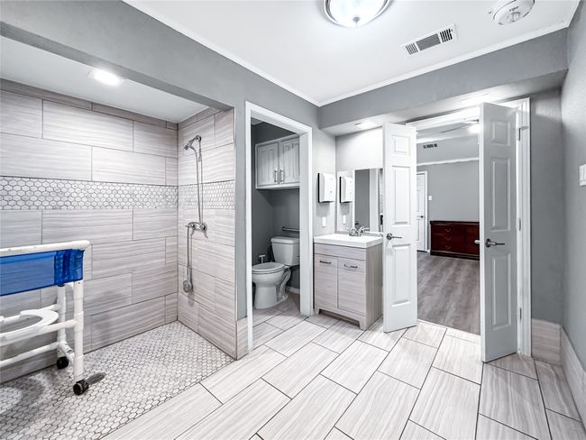 Full bath featuring tiled shower, vanity, crown molding, and wood tiled floors | Image 31