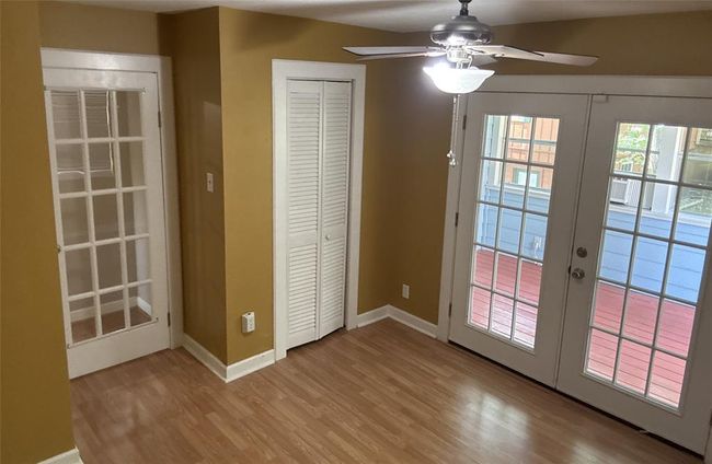Bright secondary bedroom with elegant French doors opening to a charming sunroom. | Image 11