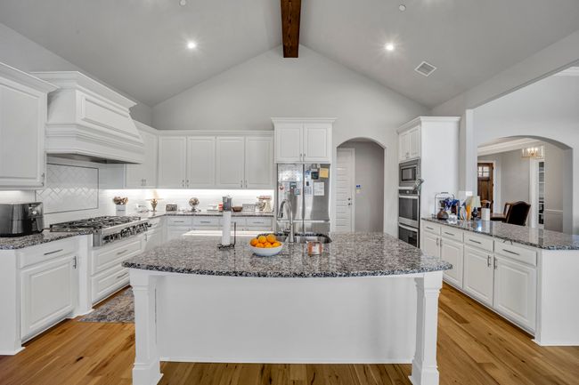 Kitchen featuring tasteful backsplash, white cabinetry, high vaulted ceiling, and appliances with stainless steel finishes | Image 9
