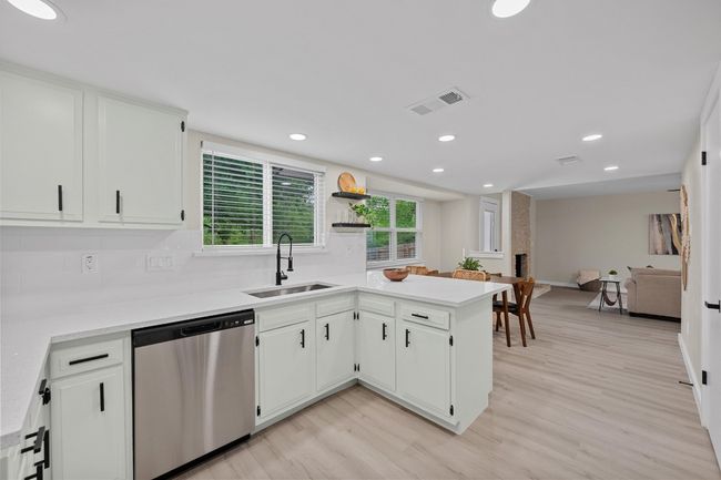 Kitchen featuring dishwasher, white cabinets, a sink, and light wood-style flooring | Image 7