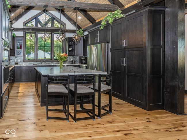 kitchen with appliances with stainless steel finishes, decorative backsplash, light wood-style floors, a sink, and hanging light fixtures | Image 15
