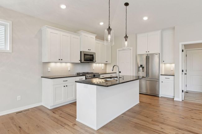 Custom cabinets features soft close, large center island, quartz and designer pendant lights | Image 13