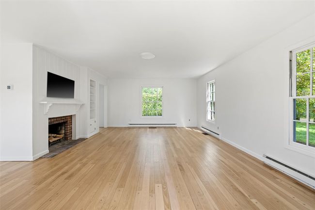 Unfurnished living room featuring a baseboard heating unit, plenty of natural light, and built in features | Image 12