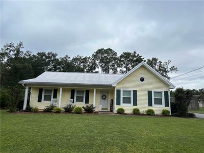 Ranch-style home with covered porch and a front yard | Image 1