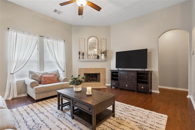 The living room offers high ceilings, a corner gas log fireplace and laminate wood flooring. | Image 6