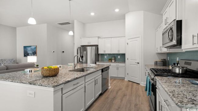 Kitchen with appliances with stainless steel finishes, a sink, white cabinetry, backsplash, and light wood-style floors | Image 6