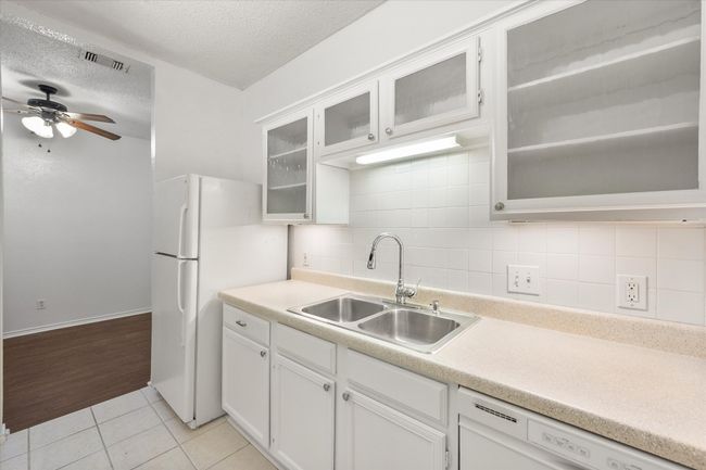 Kitchen featuring white appliances, a ceiling fan, light tile patterned flooring, a textured ceiling, and backsplash | Image 17