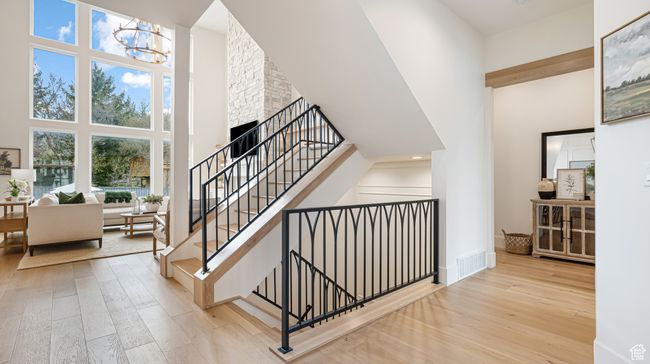 Staircase featuring a chandelier, a towering ceiling, visible vents, and hardwood / wood-style floors | Image 8