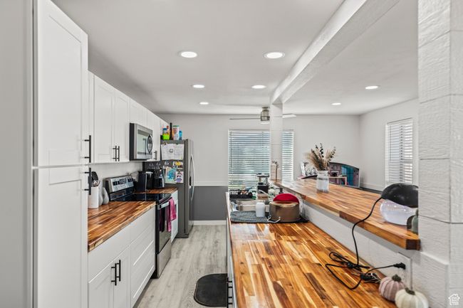 Kitchen with stainless steel appliances, butcher block counters, light wood-type flooring, plenty of natural light, and recessed lighting | Image 6