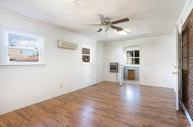 Unfurnished living room with a healthy amount of sunlight, an AC wall unit, dark hardwood / wood-style floors, and heating unit | Image 8