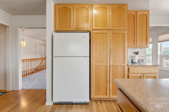 Kitchen with freestanding refrigerator, light wood-type flooring, light brown cabinetry, and light stone counters | Image 12