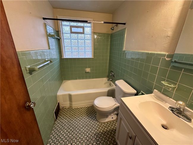 Full bath with shower / tub combination, toilet, tile walls, tile patterned floors, and vanity | Image 7