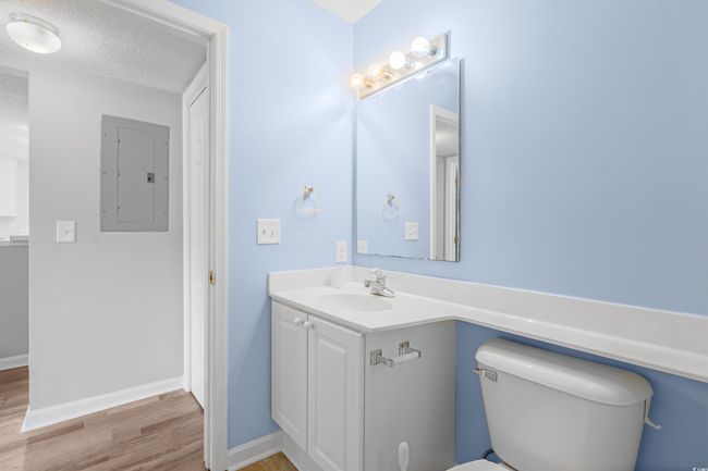 Half bath featuring electric panel, vanity, wood finished floors, and a textured ceiling | Image 20