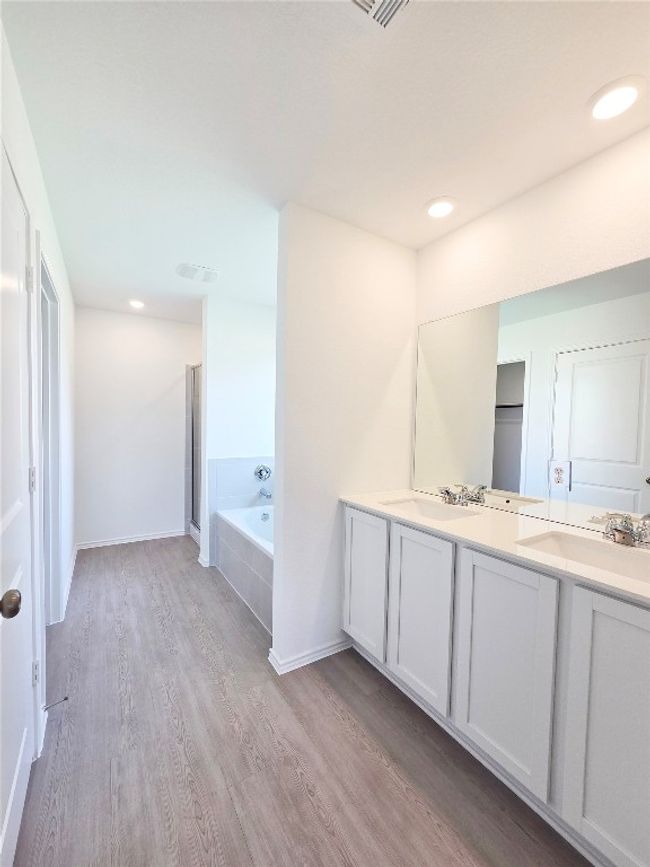 Full bath featuring wood finished floors, double vanity, a bath, and baseboards | Image 15