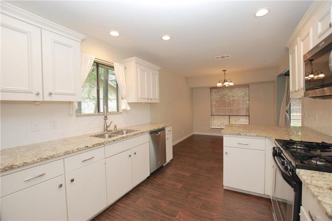 Kitchen with appliances with stainless steel finishes, a chandelier, white cabinets, decorative backsplash, and recessed lighting | Image 8