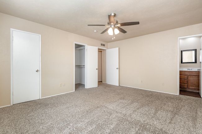 Unfurnished bedroom featuring a spacious closet, connected bathroom, carpet, and a ceiling fan | Image 17