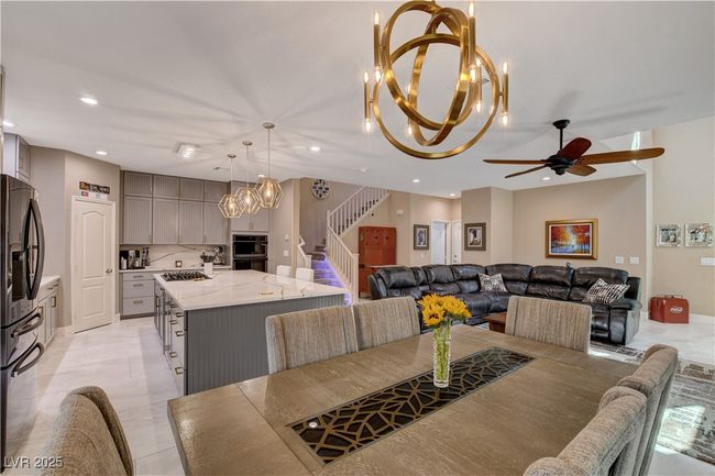 Dining area featuring ceiling fan with notable chandelier, light tile patterned flooring, stairs, and recessed lighting | Image 20