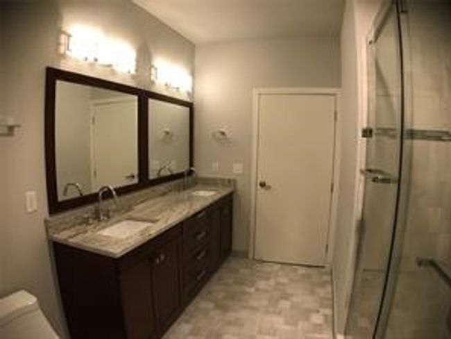 Full bath featuring a stall shower, double vanity, and toilet | Image 12