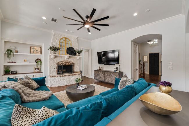 Living area with wood finished floors, ceiling fan, arched walkways, a fireplace, and recessed lighting | Image 13