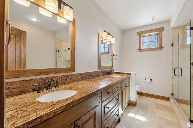 Bathroom featuring double vanity, a sink, toilet, and a shower stall | Image 17