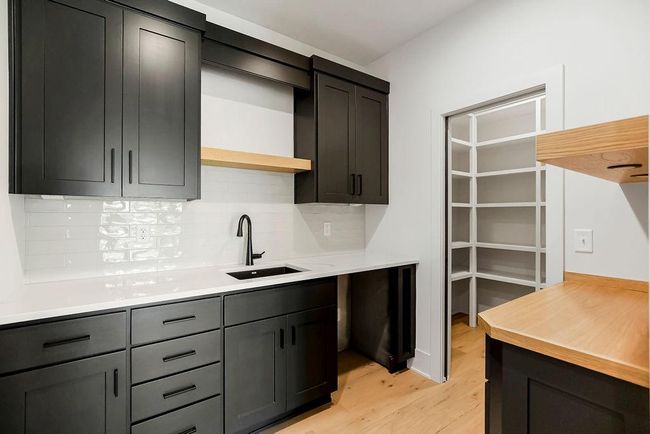 Kitchen featuring a sink, light wood-style flooring, backsplash, open shelves, and light countertops | Image 12