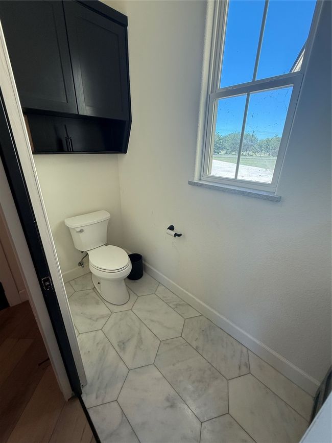 Bathroom featuring toilet and marble look tiles | Image 24