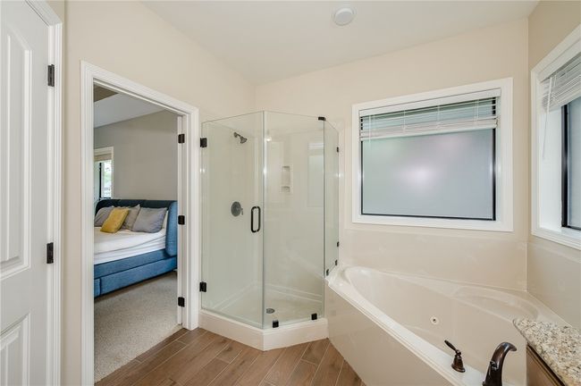 Bathroom with a tub with jets, wood finished floors, ensuite bathroom, and a stall shower | Image 18