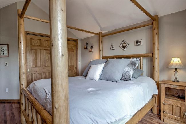 Bedroom featuring wood finished floors, lofted ceiling, and ornate columns | Image 35