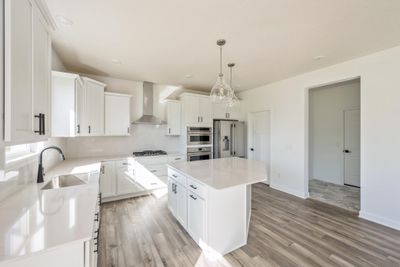 (Photo of an inventory home, actual homes finishes will vary) Large gourmet kitchen anchored by a large kitchen island. Features stainless steel appliances, quartz counters, a walk-in pantry, LVP floors, double ovens and more! | Image 2