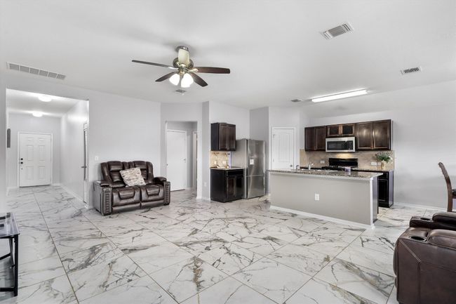 Living area with a ceiling fan, baseboards, and light marble finish flooring | Image 4