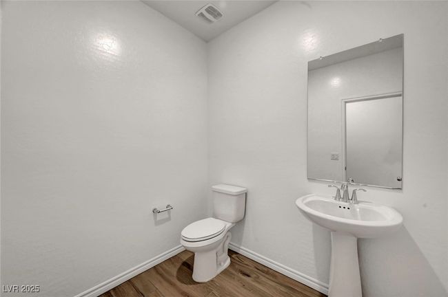 Half bath with a sink, visible vents, baseboards, toilet, and wood finished floors | Image 27