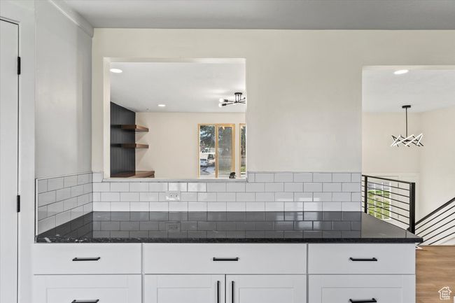 Kitchen featuring backsplash, wood finished floors, dark stone countertops, white cabinets, and recessed lighting | Image 10
