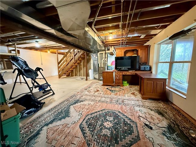 Below grade area featuring heating unit, stairs, and a desk | Image 35