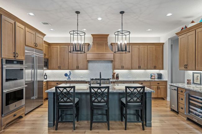 Kitchen featuring beverage cooler, 6-bunren range top, light wood-style flooring, built in appliances, and custom exhaust hood | Image 13